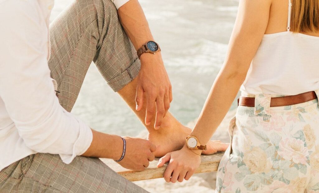 Sieviete un vīrietis neitrālās krāsas apģērbā ar koka rokas pulksteņiem