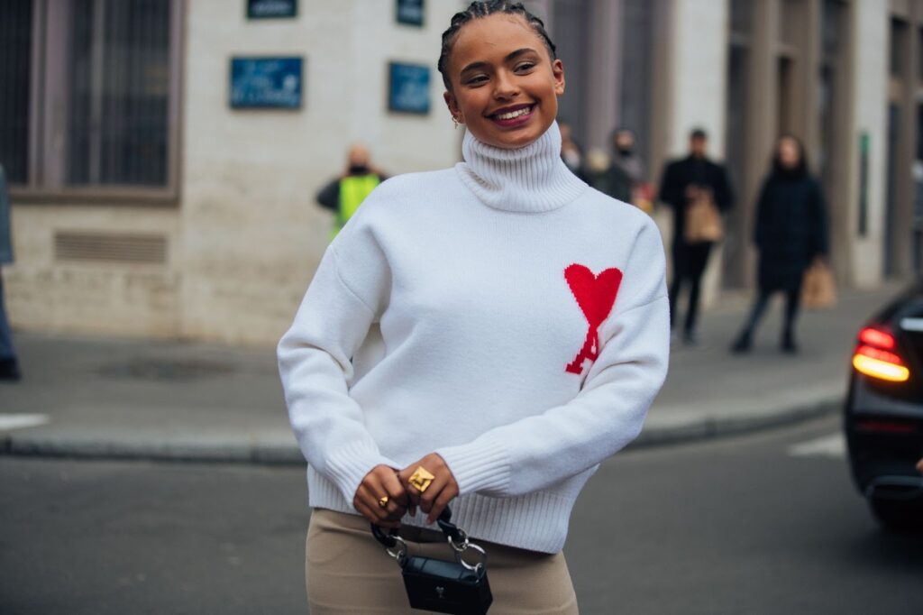 Smaidīga sieviete baltā džemperī ar sirsniņu rakstu