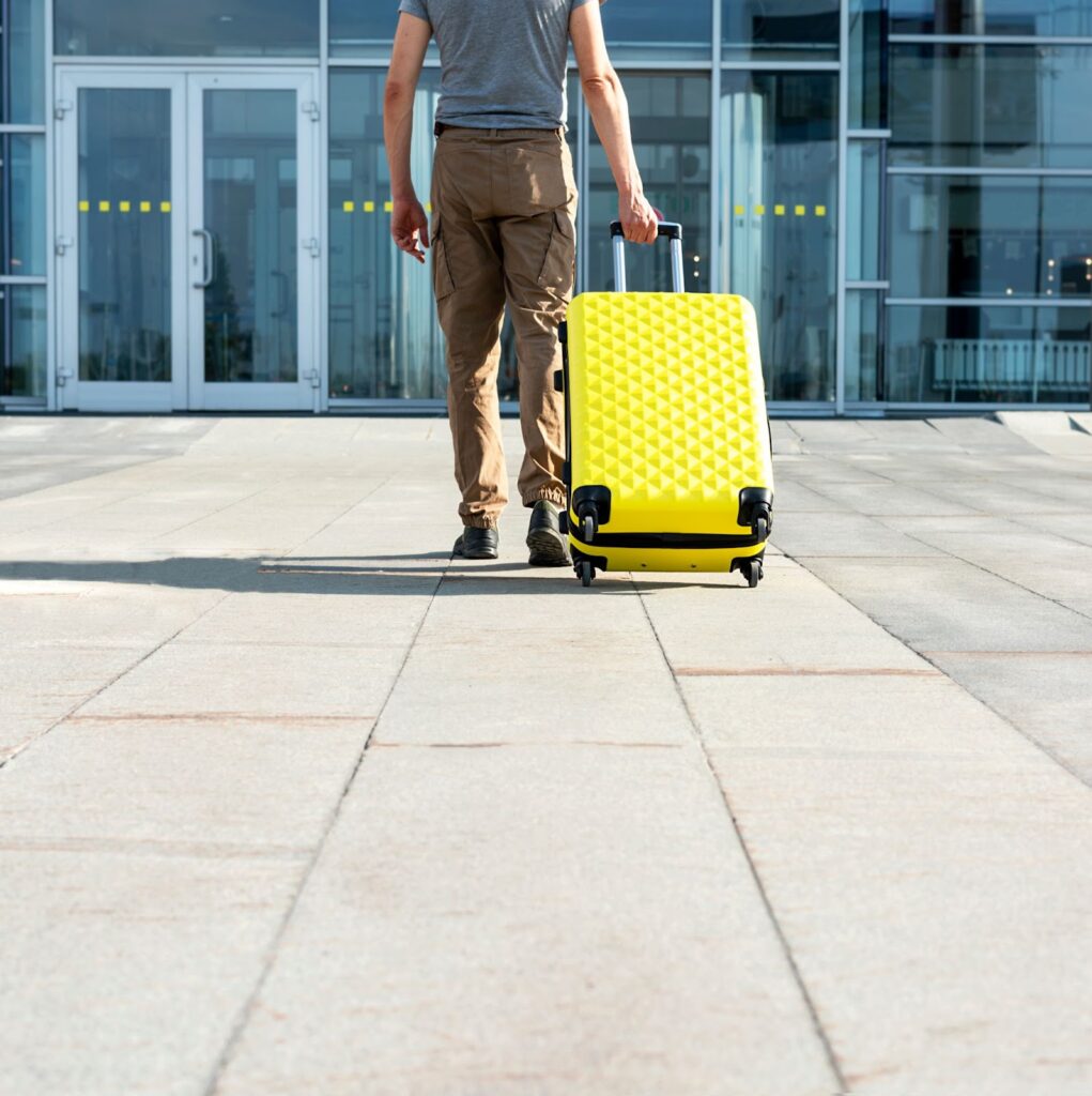 Vīrietis ar cietu koferi dzeltenā krāsā