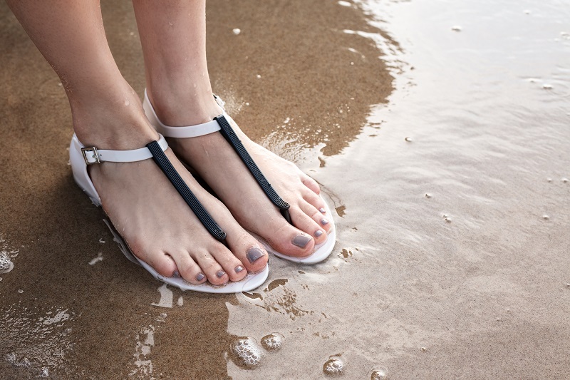 Sieviešu pludmales sandales jūras krastā ar siksniņu ap potīti