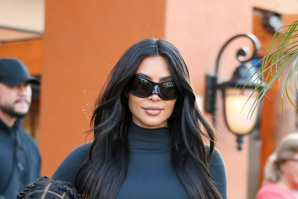 Modele melnajā kreklā ar augstu apkakli un modernajām saulesbrillēm